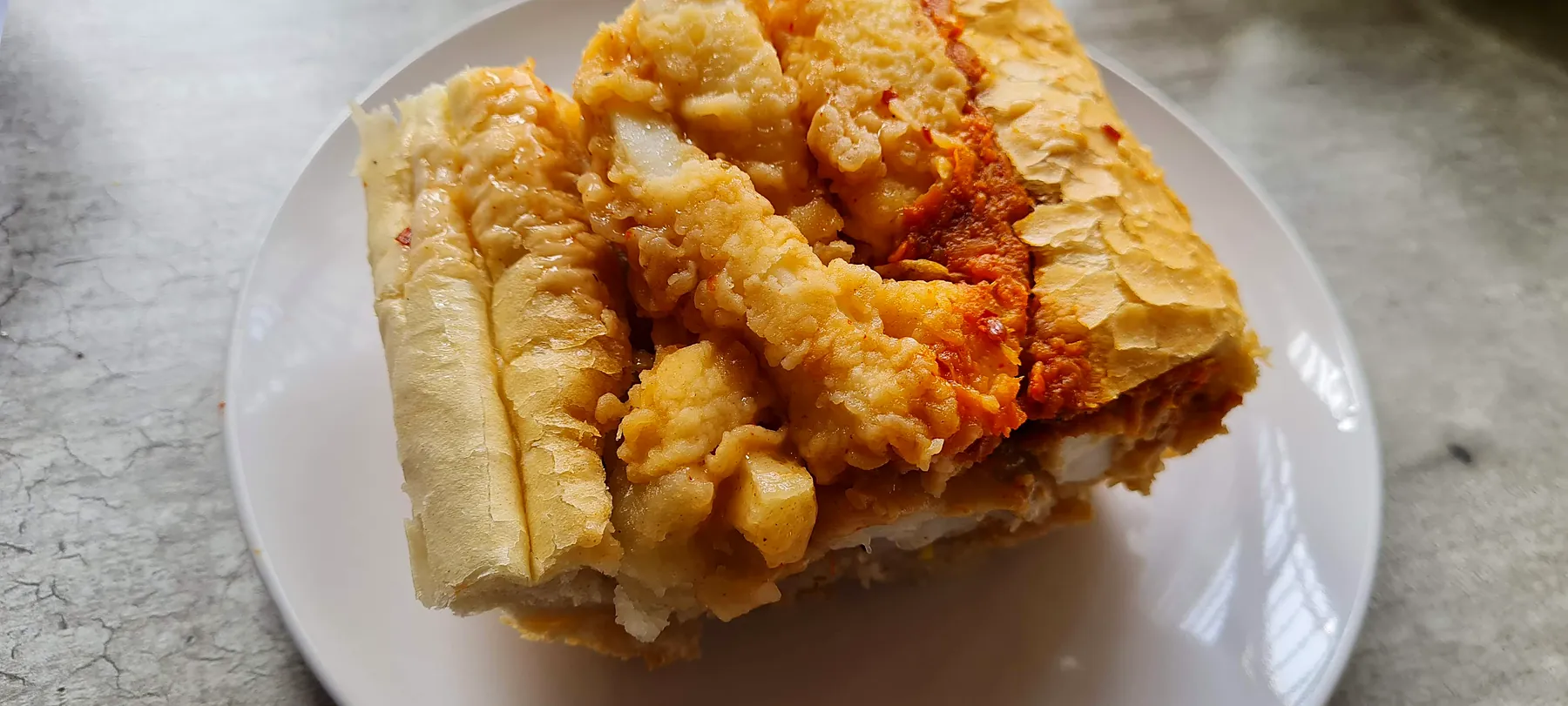 A calamari Gatsby cut open on a white plate.