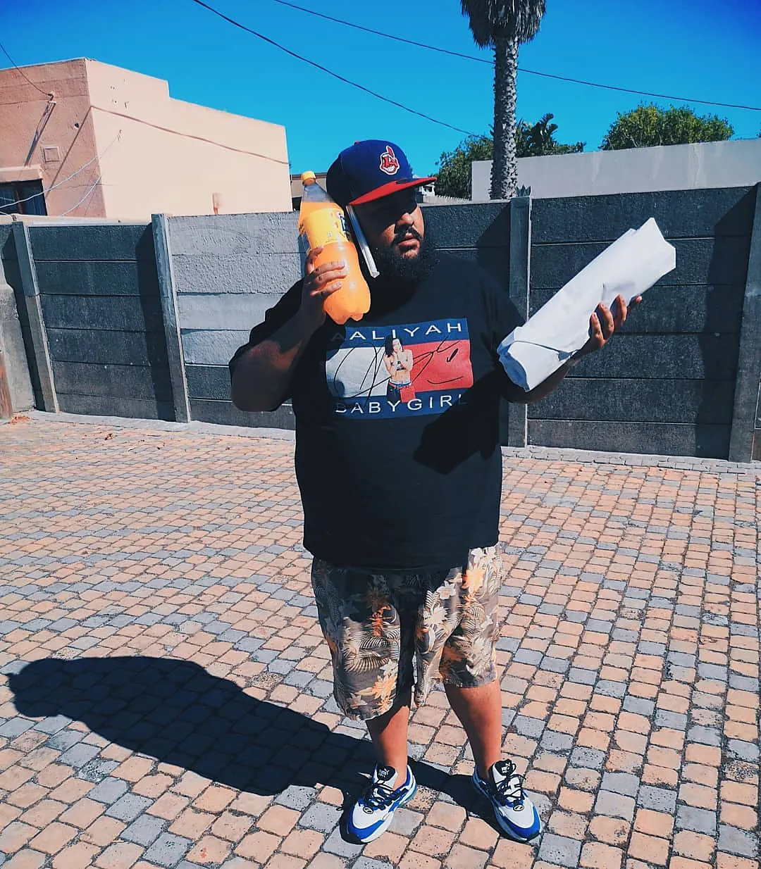 A customer outside with a wrapped Gatsby under one arm and a bottle of Jive in the other hand.