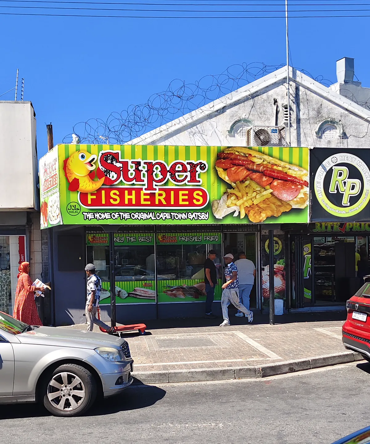 The Super Fisheries shopfront on Old Klipfontein Road under a blue sky, with the striped fascia, the fish logo and a Gatsby on the sign.